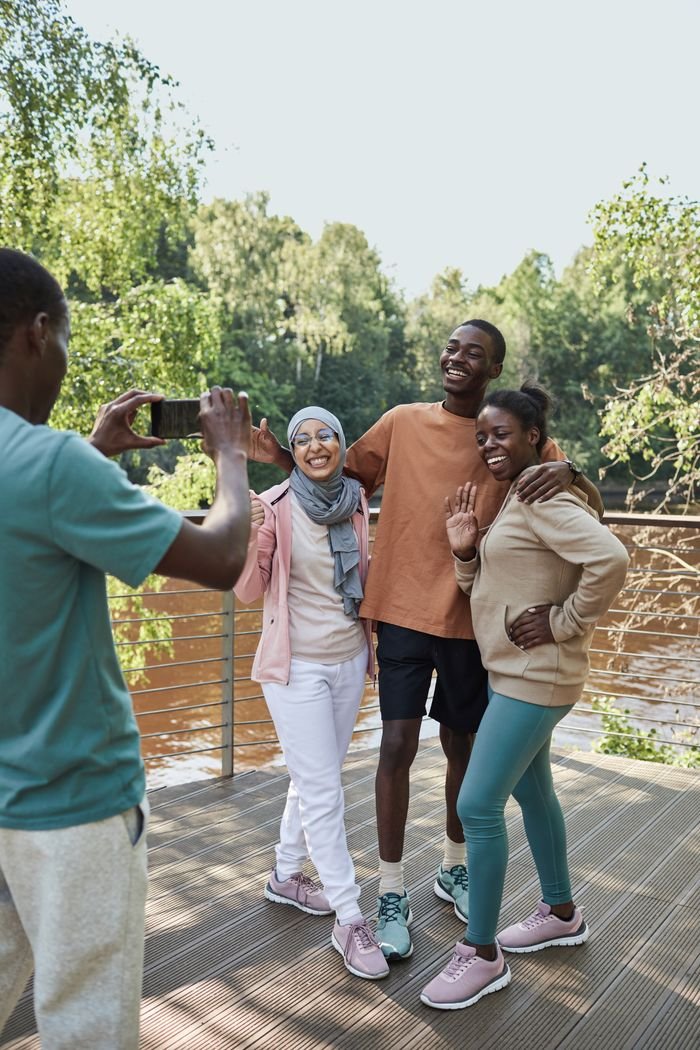 Group of diverse friends posing happily by a lakeside deck in the summer.